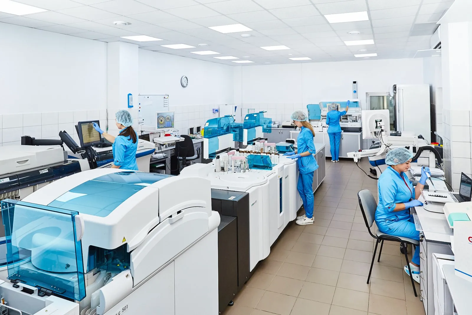 Laboratory staff processing samples on diagnostic analysers