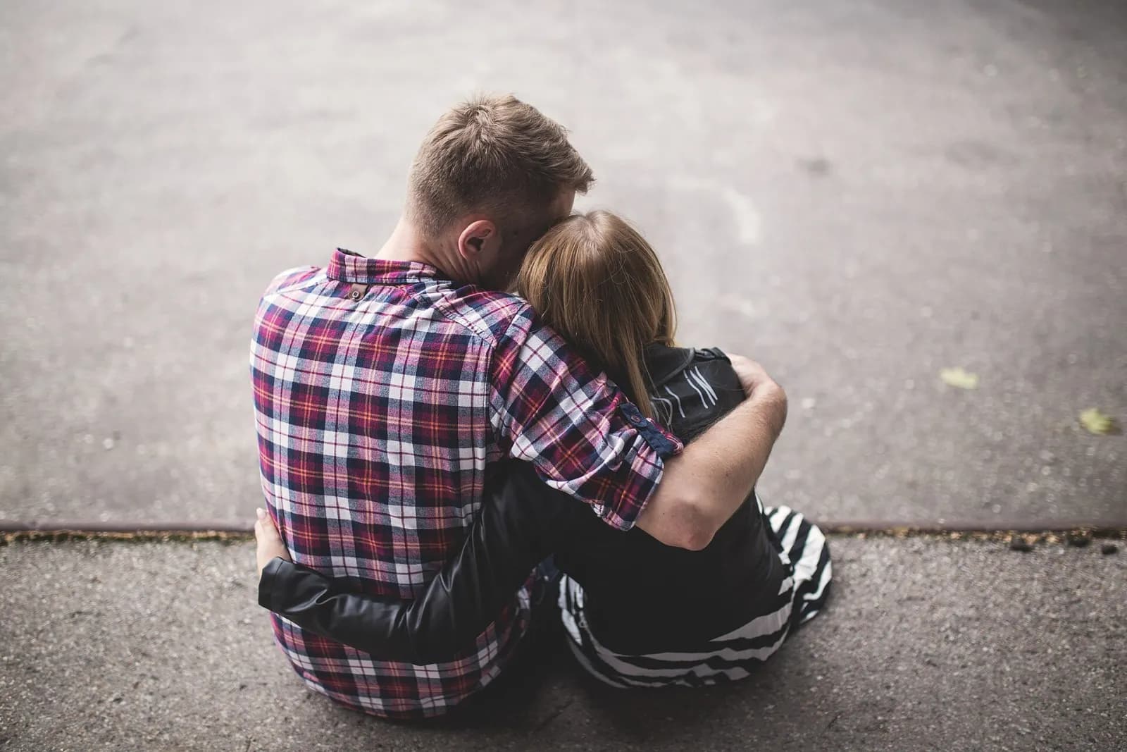 A couple sitting on the ground hugging, seen from behind