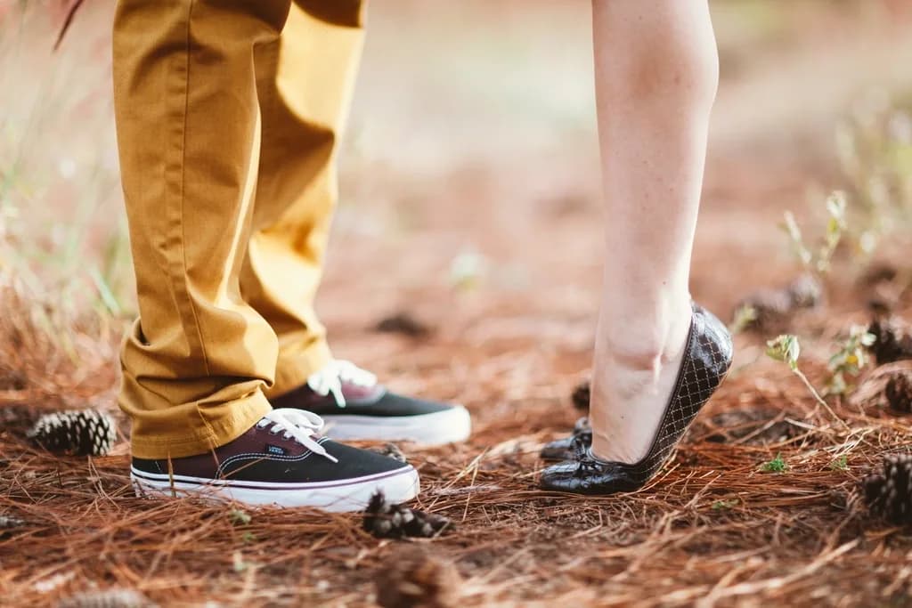 A couple standing close together, one on tiptoe, seen from the knees down